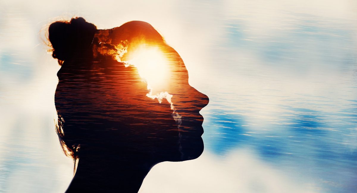 The Light Head. Silhouette of young woman on sky background with sun in her head.